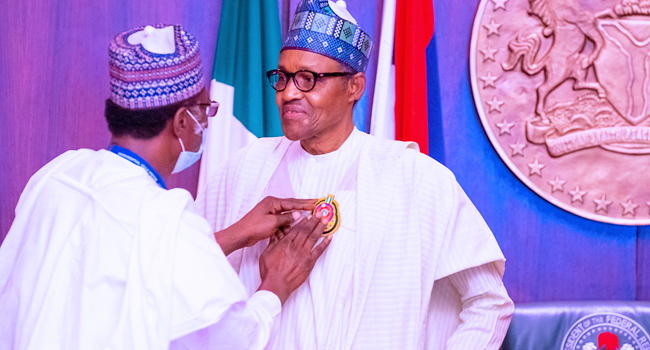 President Buhari being decorated by the National Chairman Nigerian Legion Brig. Gen. Adakole Jones Akpa (Rtd) as he presides over the Emblem Appeal Launch for the 2021 Armed Forces Remembrance Day Celebration in State House on 28th Oct 2020.
