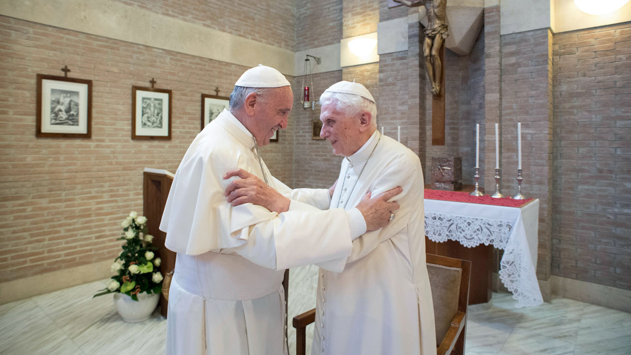 (FILES) This handout picture released on February 15, 2018 by the Vatican press office shows Pope Francis (L) greeting Pope Benedict XVI at the Vatican. – Both Pope Francis and his predecessor, former pope Benedict XVI, have received the coronavirus vaccine, the Vatican said on January 14, 2021. (Photo by HO / OSSERVATORE ROMANO / AFP) /