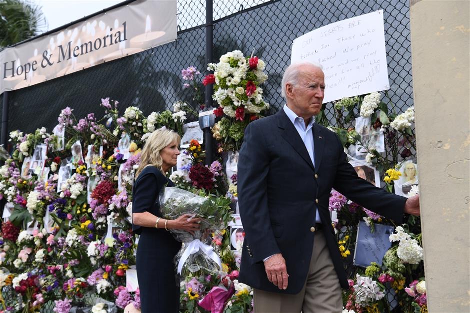 US President Joe Biden (R) and US First Lady Jill Biden visit a photo wall near the partially collapsed 12-story Champlain Towers South condo building in Surfside, Florida, July 1, 2021. (Photo by SAUL LOEB / AFP)