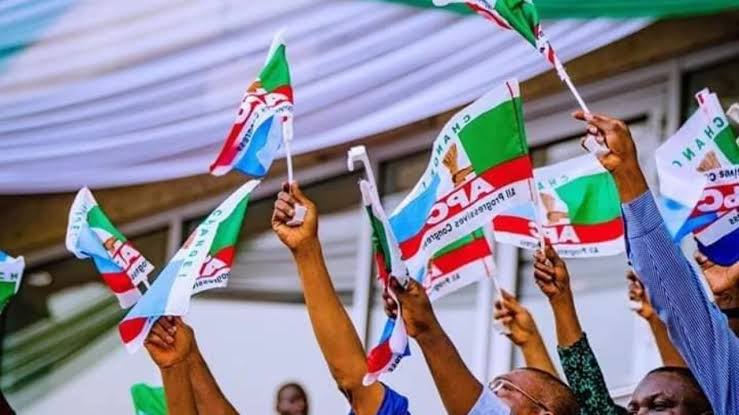 A photo of hands holding All Progressives Congress (APC) party flag.